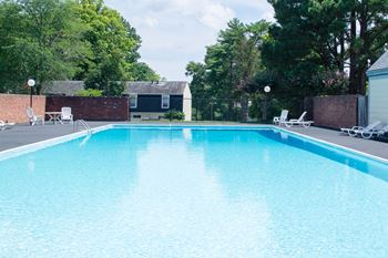 a swimming pool with chaise lounge chairs and trees in the background